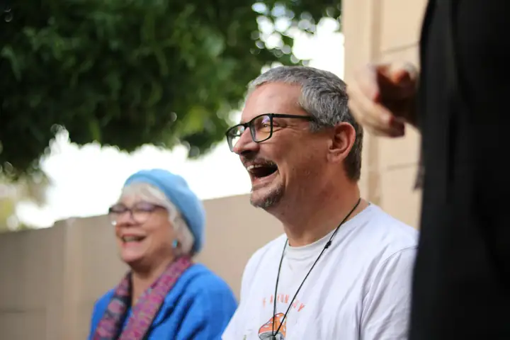 An older man and woman laughing together outdoors.