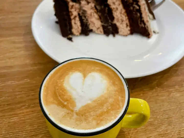 A slice of chocolate cake beside a cup of coffee.