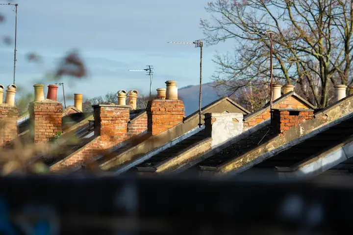 A row of brick chimneys along a terrace of tiled roofs.